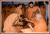 Swamishri sprinkles the holy water of Mansarovar on sadhus one by one