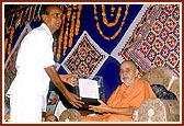 An official of the local Municipal Corporation presents a proclamation of honor to Swamishri during an assembly