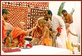 Swamishri ritually applies chandan and gives the janoi to Brahmin batuks