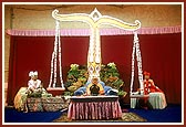 Swamishri's morning puja on Dev Diwali: An Annakut of fresh vegetables with Swamishri's seat arranged between a large scale