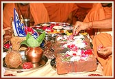 Swamishri performs the stone-laying rituals of a guesthouse with petals, rice grains, etc