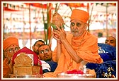 Swamishri holds the auspicious pot and shrifal during the rituals