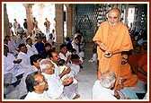 Swamishri blesses the devotees and their children by showering rice grains