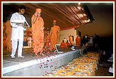 Swamishri showers flower petals over the mantra notebooks written by the devotees