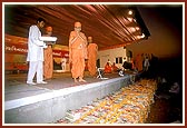 Swamishri showers flower petals over the mantra notebooks written by the devotees