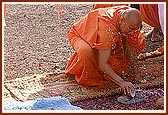 Pujya Ishwarcharan Swami breaks the coconut and offers it to Shri Harikrishna Maharaj