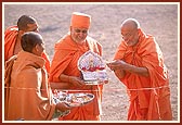 Pujya Ishwarcharan Swami breaks the coconut and offers it to Shri Harikrishna Maharaj