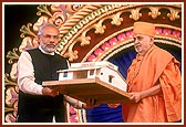 Swamishri presents a model home to the Chief Minister, symbolizing the Earthquake Rehabilitation Work carried out by the BAPS - 9 villages and colonies and 43 school reconstructed