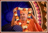 Swamishri prepares to offer a garland to one of the invited guests