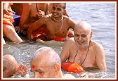 Swamishri bathes in the river surrounded by senior sadhus