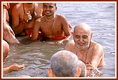 Swamishri bathes in the river surrounded by senior sadhus