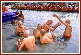 Senior sadhus sprinkle the holy water on each other