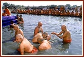 Senior sadhus sprinkle the holy water on each other