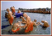 Senior sadhus sprinkle the holy water on each other