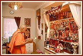 Swamishri performs arti of a devotee's ghar mandir (home shrine)