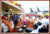 Swamishri, sadhus and devotees engaged in devotional singing, with the Sydney Opera House in the background