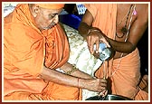 Swamishri bathes Harikrishna Maharaj with water from the Pacific Ocean