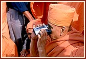 Swamishri sees the grandeur of the monument through a pair of binoculars