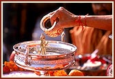 Bathes Shri Harikrishna Maharaj with water as part of the rituals