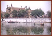 Swamishri, senior sadhus and trustees arrive by boat for the murti pratishtha ceremony of Shri Sarveshwar Mahadev in the lake called Sursagar. In the background is the famous Nyaya Mandir