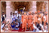 While departing, Swamishri raises a flag and responds to the devotees seated for darshan