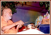 Swamishri sprinkles fragrant colored water on Shri Harikrishna Maharaj