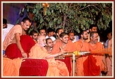 Swamishri sprays holy, colored water on the devotees 