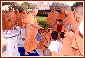 Swamishri squirts color on a child