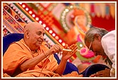 Swamishri sprays the sanctified colored water on the distinguished guests