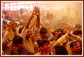 Devotees ecstatically fold their hands to be blessed with the shower of holy, colored water