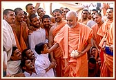 A young boy gives a ball of flowers to Swamishri to place it on the shrine. Swamishri then tells the boy to accompany him during the pradakshina of the Smruti mandir