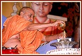 Out of reverance and devotion, Swamishri ritually bathes Shri Harikrishna Maharaj with panchamrut and water