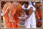 Swamishri pours cement into the foundation-pit