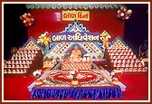 Swamishri performs his morning puja on Children's Day. In the backdrop are plaques for balaks who excelled in recitation and other competitions