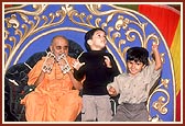 On Children's Day assembly, little children dance to the singing of a bhajan during a kirtan concert. Swamishri participates by playing the kartal