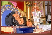 Swamishri engaged in bhajan and darshan while Thakorji is being driven in a remote controlled chariot