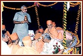 The Chief Minister holds the sacred kalash while Swamishri is seated with folded hands during the Vedic ceremony