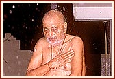 Swamishri bathes in the rain pouring from the eaves outside his room