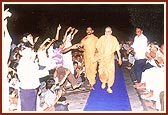 Children joyfully dance during Swamishri's evening routine walk 