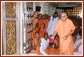 Swamishri offers a ball of roses at the feet of Thakorji
