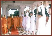 Swamishri raises his hands to encourage the kishores who are saying the rosary