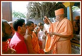 Swamishri sprinkles the sanctified water on the devotees present