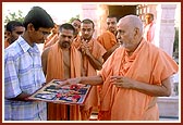 A devotee holds out a murti for his ghar mandir for Swamishri to sanctify