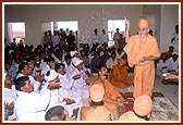 Swamishri showers sanctified rice grains on the devotees