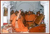 Swamishri applies chandlo to devotees, offers prayers and sanctifies the mandir office with flower petals