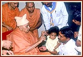 Swamishri performs Chol karma - snipping of hair from a balak's head