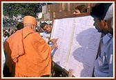 Swamishri showers flowers and understands the plan for the Hari mandir to be constructed in Udhna - a suburb of Surat