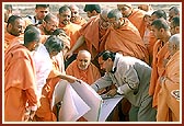 Swamishri observes the plans and discusses about the complex. In the background are sections of the parikrama
