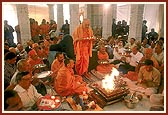 Beneath the mandir dome, Swamishri and devotees perform arti during the vastu puja rituals