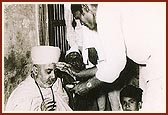 Tukaram Ragho,a devotee, performs pujan of Swamishri during a home-visit (padhramani), 1976, Mohadi